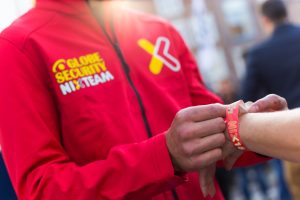 Medewerker van Globe Security NIXTEAM plakt een NIX18-polsbandje op een evenement