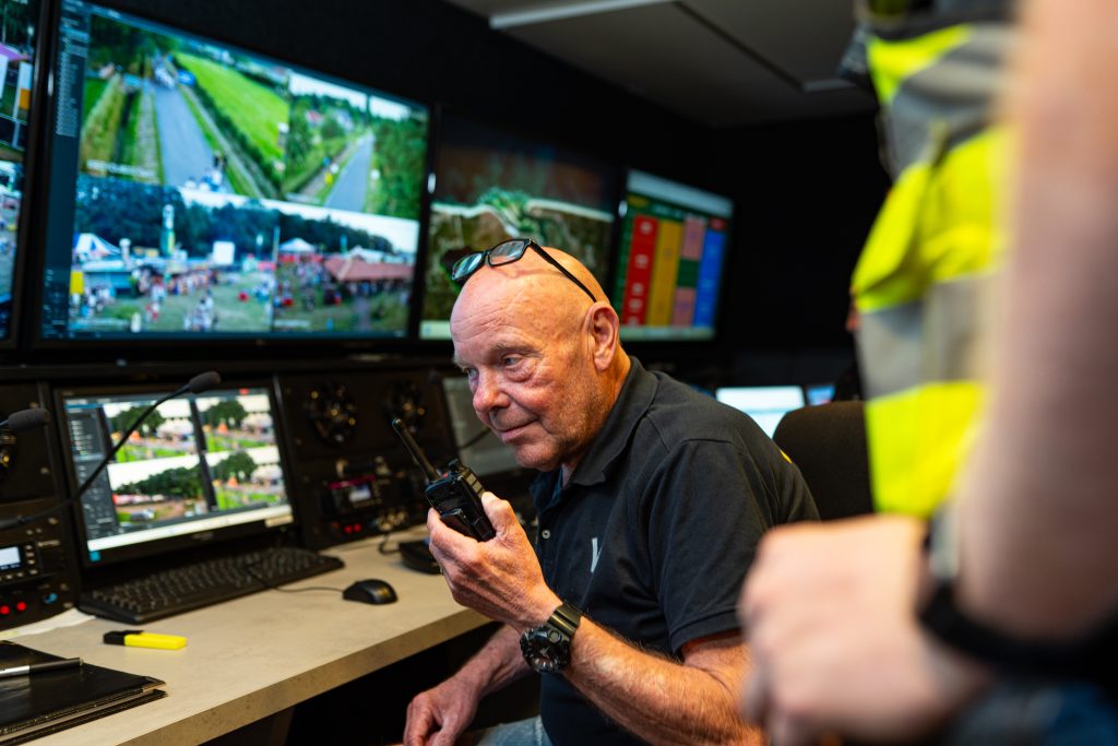 Beveiligingsmedewerker communiceert via portofoon in de mobiele communicatie unit met bewakingsmonitoren.
