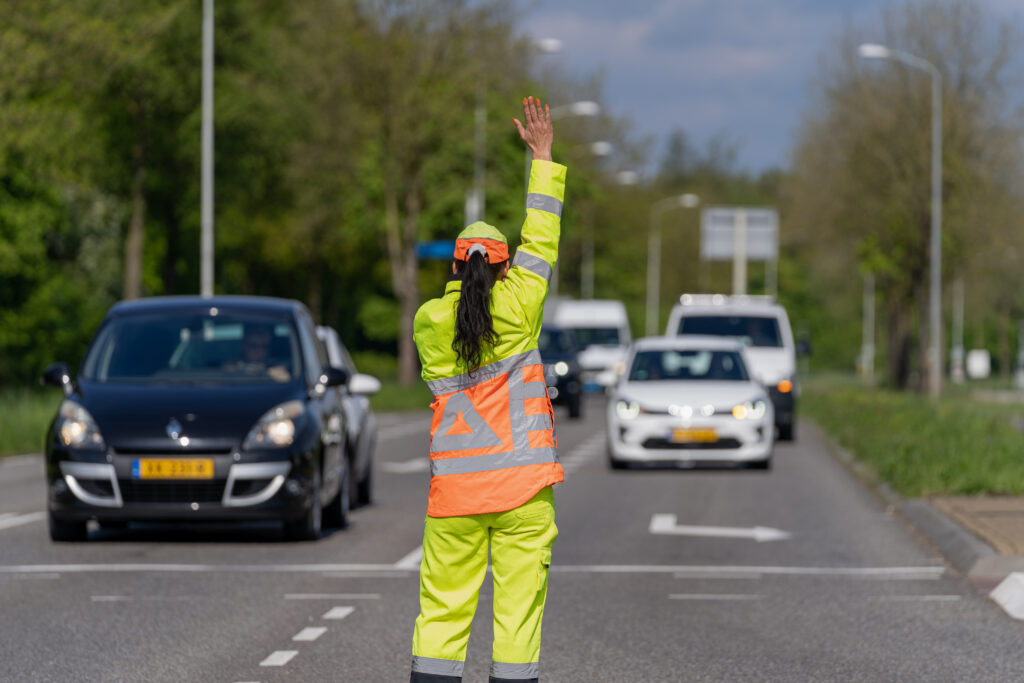 Verkeersregelaar in fluorescerende kleding die verkeer regelt op een drukke weg