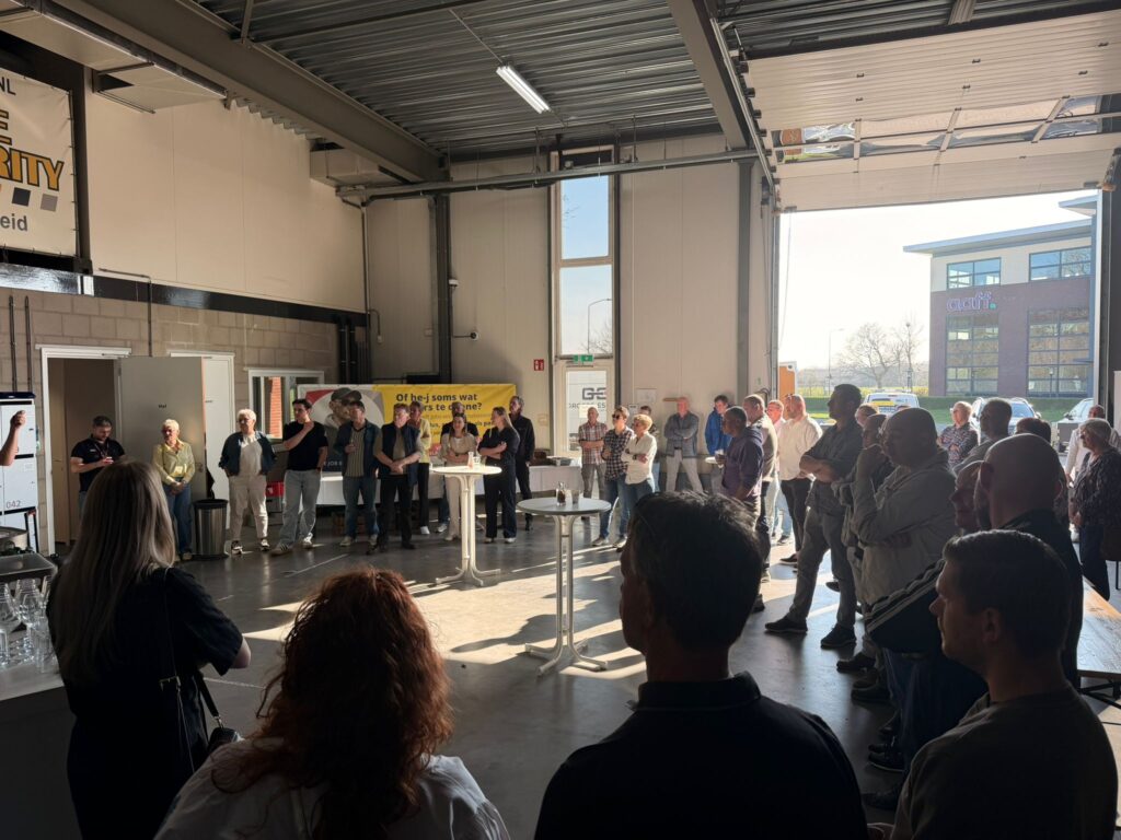 Groep mensen verzameld in een werkplaats tijdens een netwerkbijeenkomst met presentatie