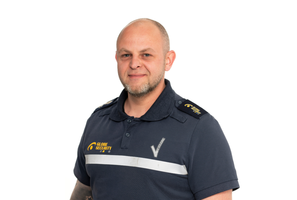 Portret van een beveiliger in Globe Security-uniform tegen een neutrale achtergrond, met professionele en vriendelijke uitstraling.