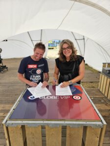 Twee mensen ondertekenen documenten aan een Globe VIP-tafel tijdens een evenement.